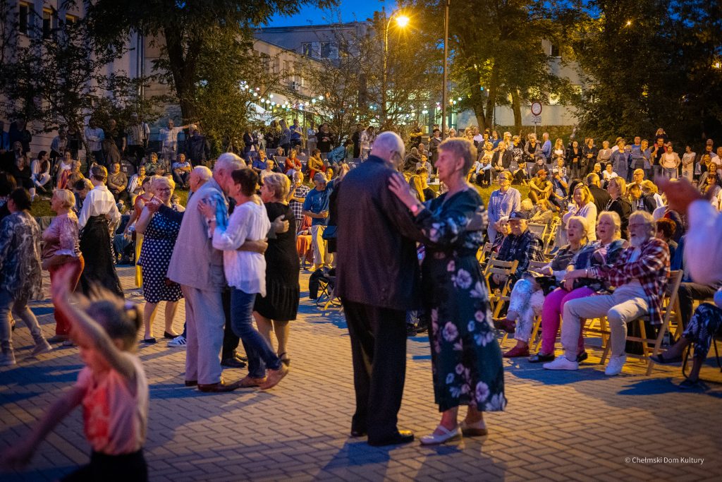 Pary tańczą na placu podczas wieczornego wydarzenia plenerowego.