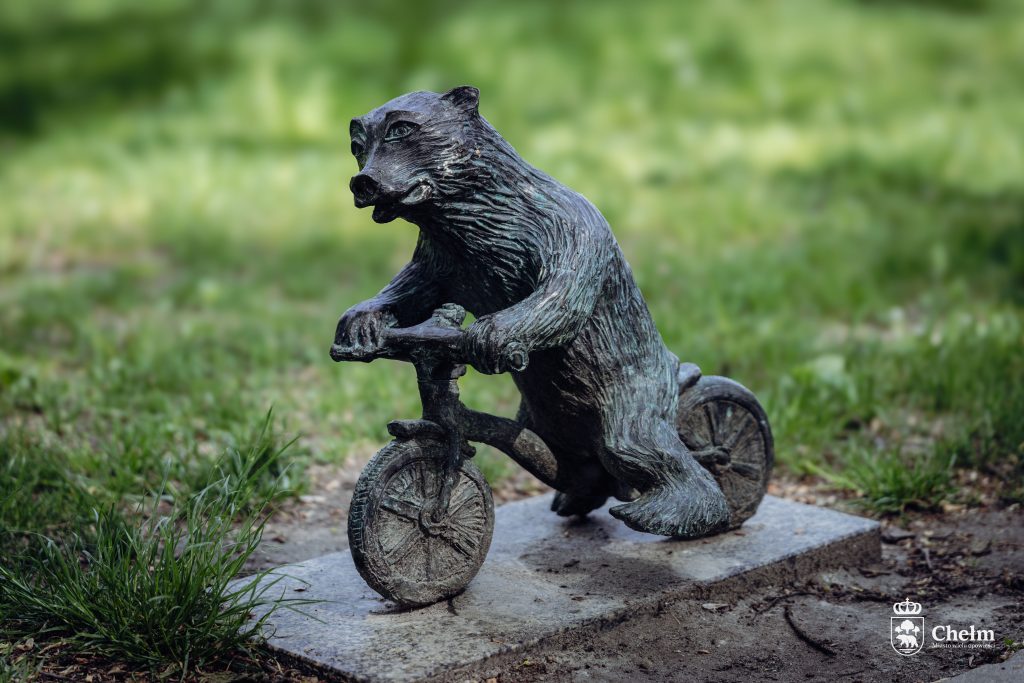 Figurka misia chełmisia jadącego na rowerze