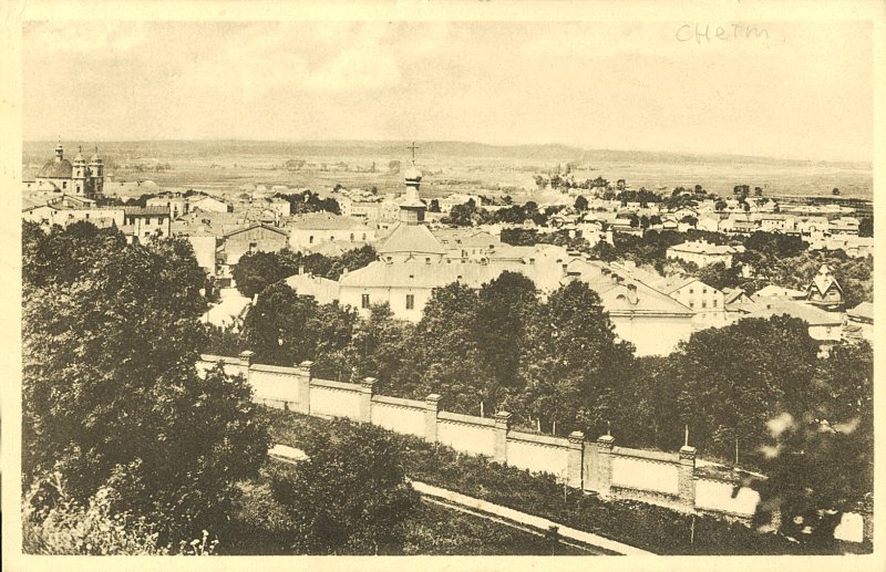 Historyczne zdjęcie Chełma z początku XX wieku, przedstawiające panoramę miasta z zabudową i kościołami.